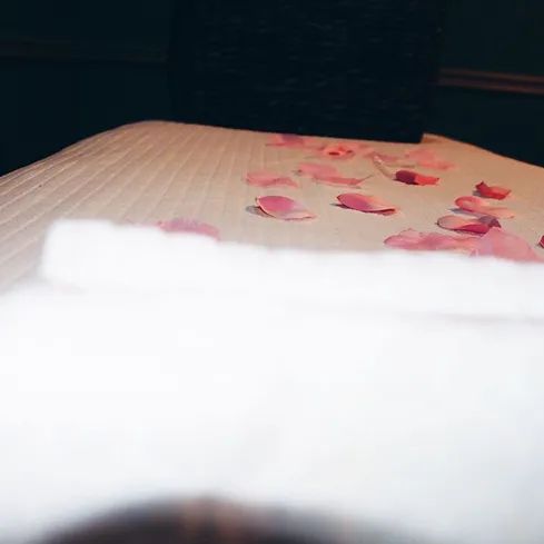 A bed with pink rose petals on it.