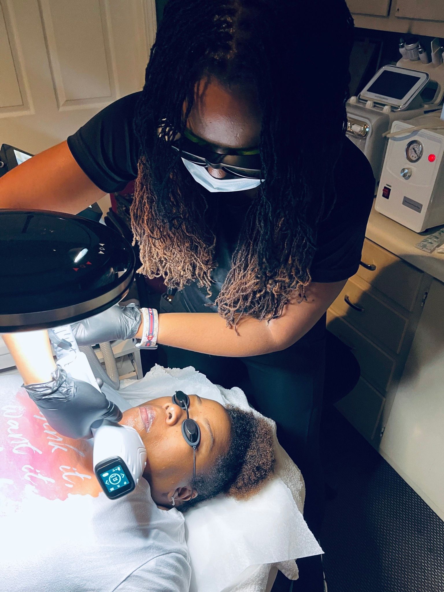 A woman is giving a woman a laser treatment on her face.