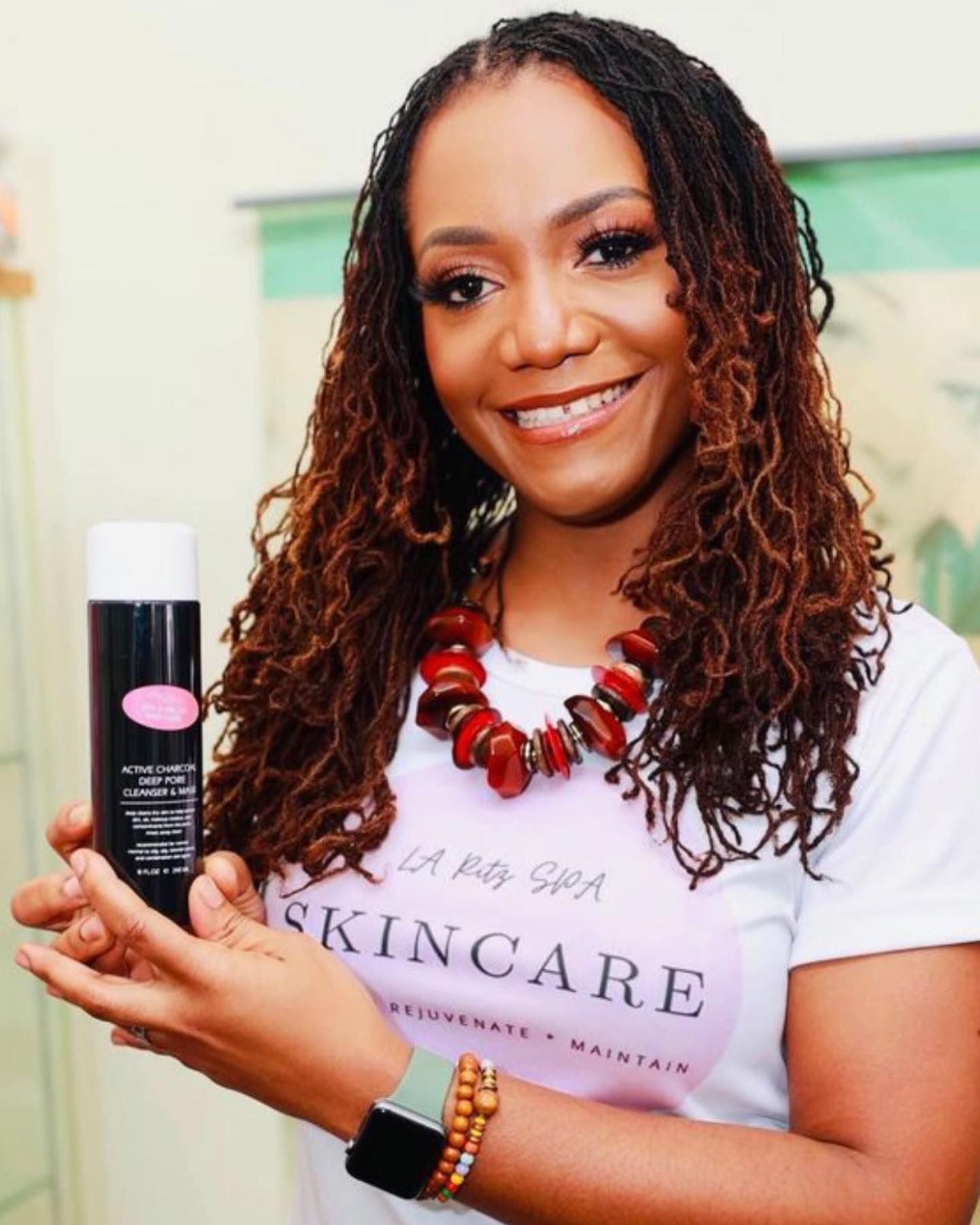 A woman wearing a t-shirt that says skincare is holding a bottle