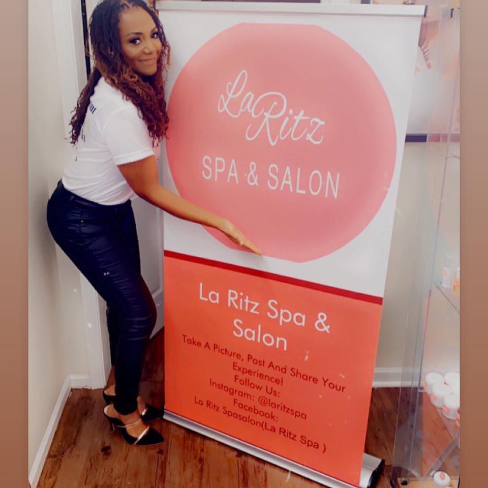 A woman is holding a sign for la ritz spa & salon