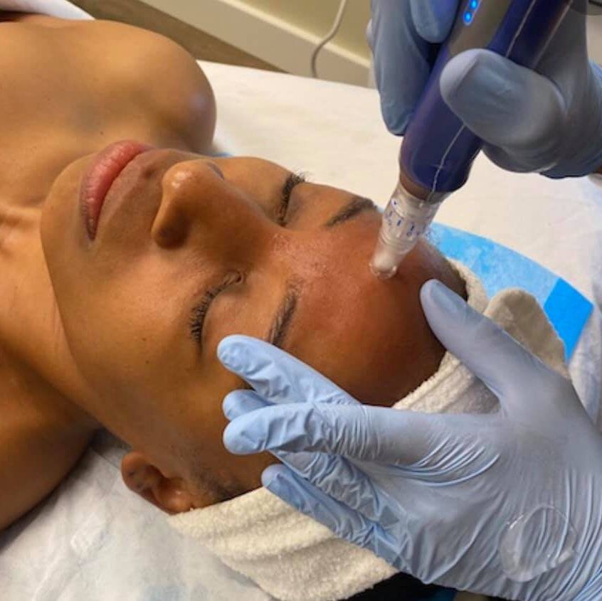 A woman is laying on a bed getting a treatment on her face