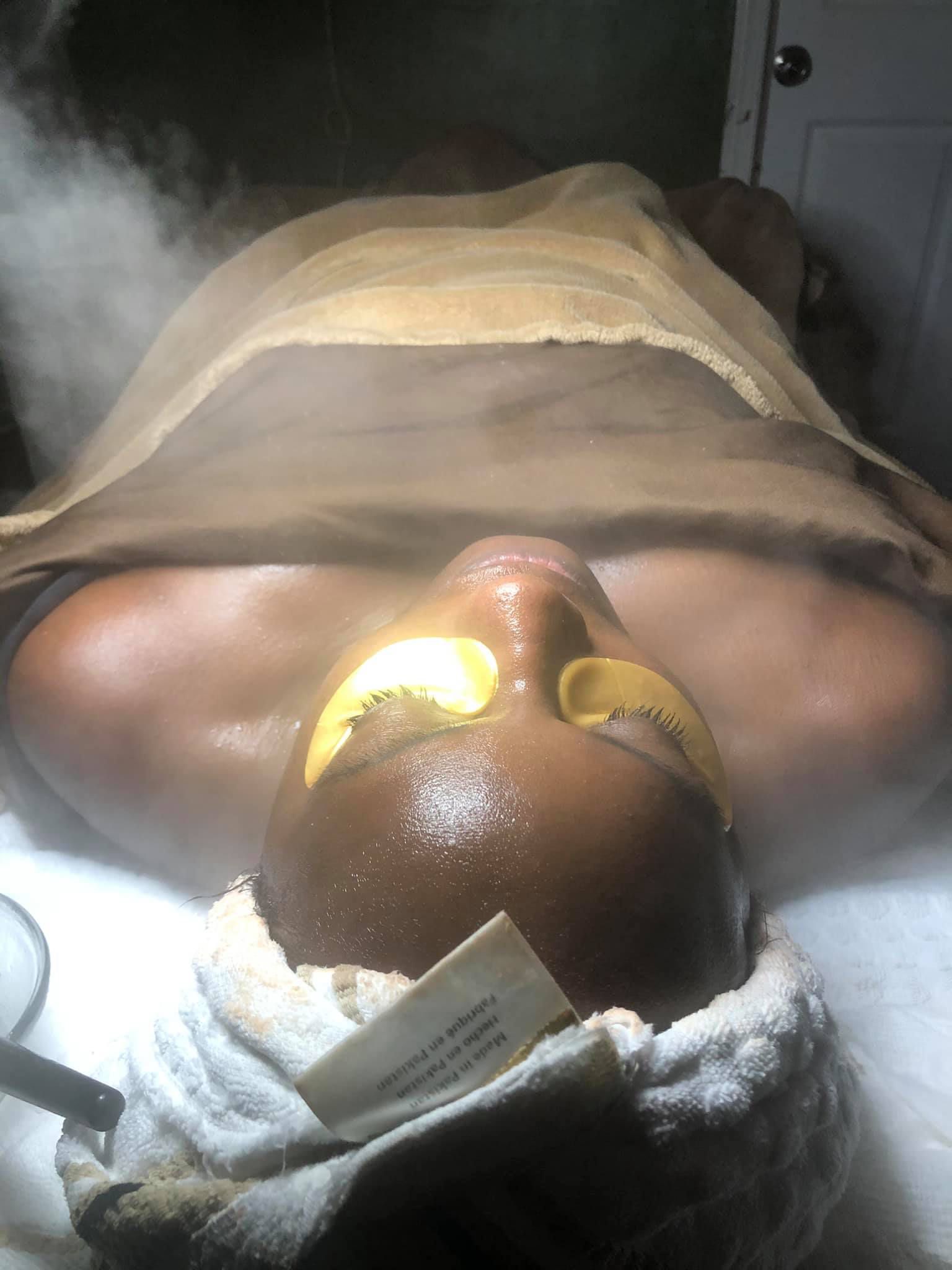 A woman is laying on a bed with a towel around her head.