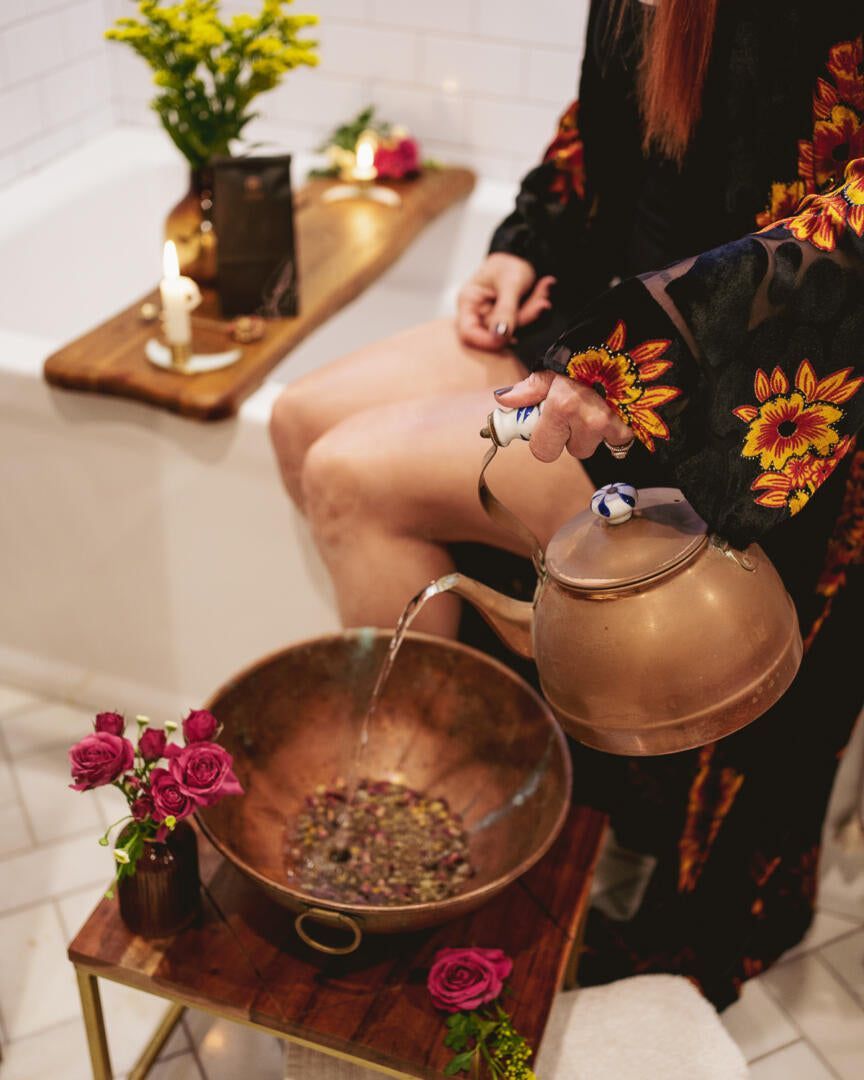 A woman is sitting in a bathtub pouring water into a bowl