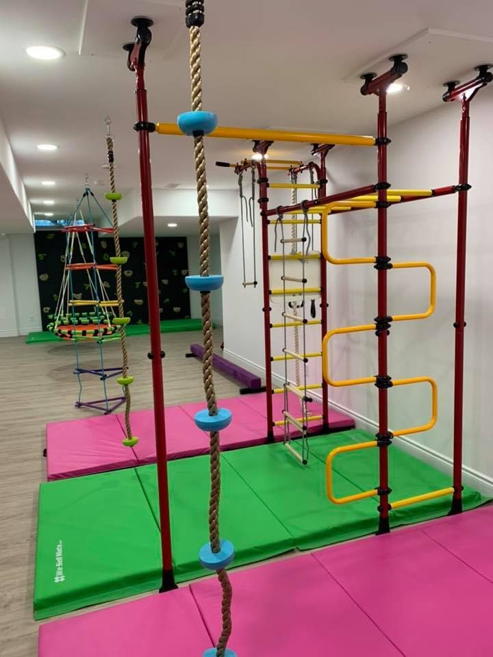 A gym with a rope climbing wall and a pink mat