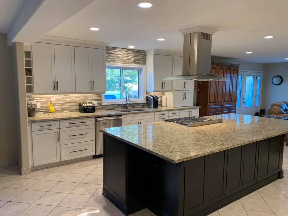 A kitchen with white cabinets , granite counter tops , stainless steel appliances and a large island.