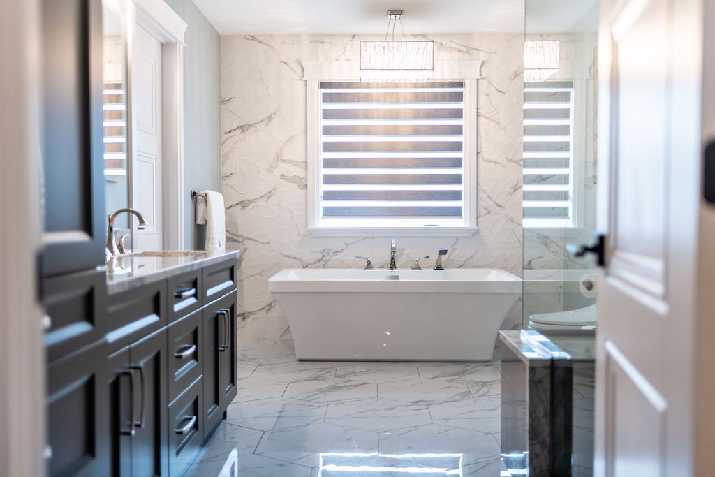 A bathroom with a tub , sink , mirror and window.