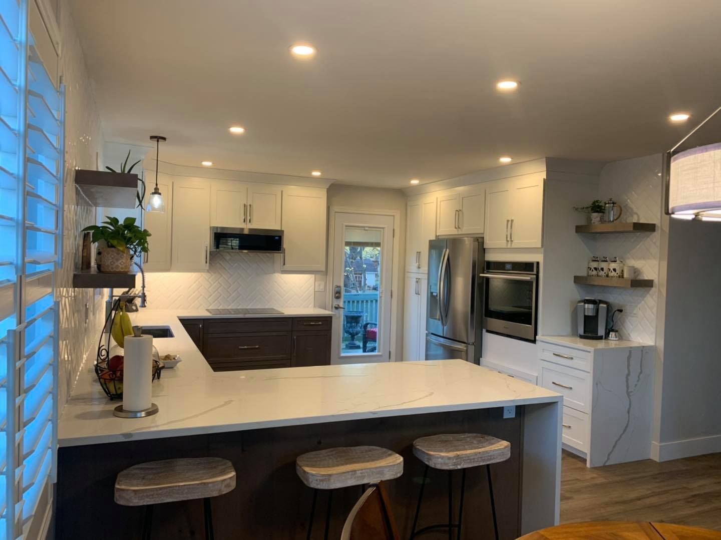 Modern kitchen with white cabinets, dark island, and bar stools.