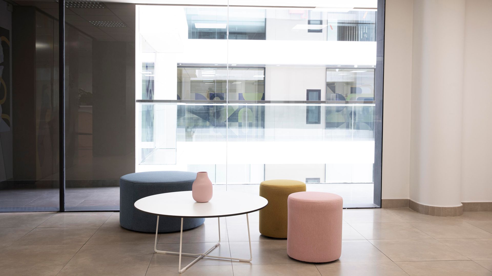 A room with a table and ottomans in front of a window.
