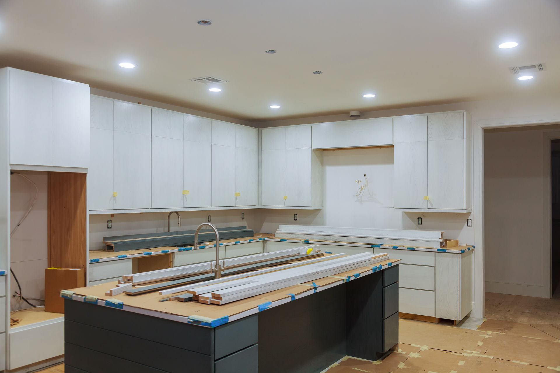 A kitchen under construction with white cabinets and a large island.