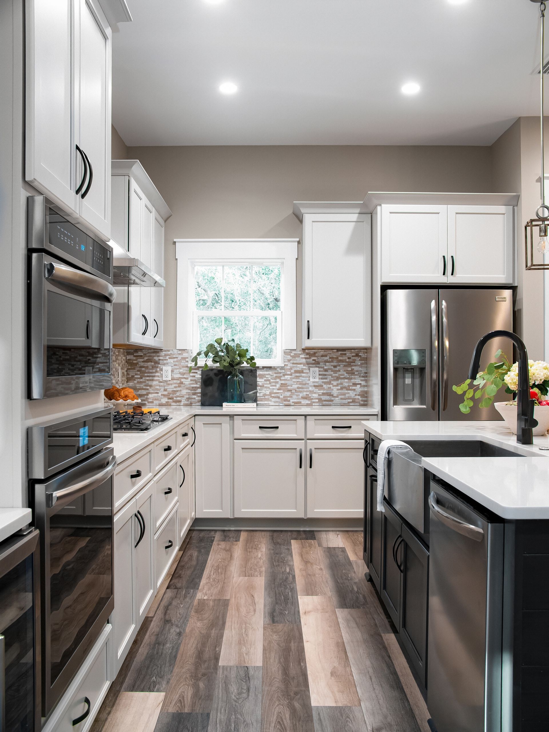 A kitchen with white cabinets , stainless steel appliances , a sink , and a refrigerator.