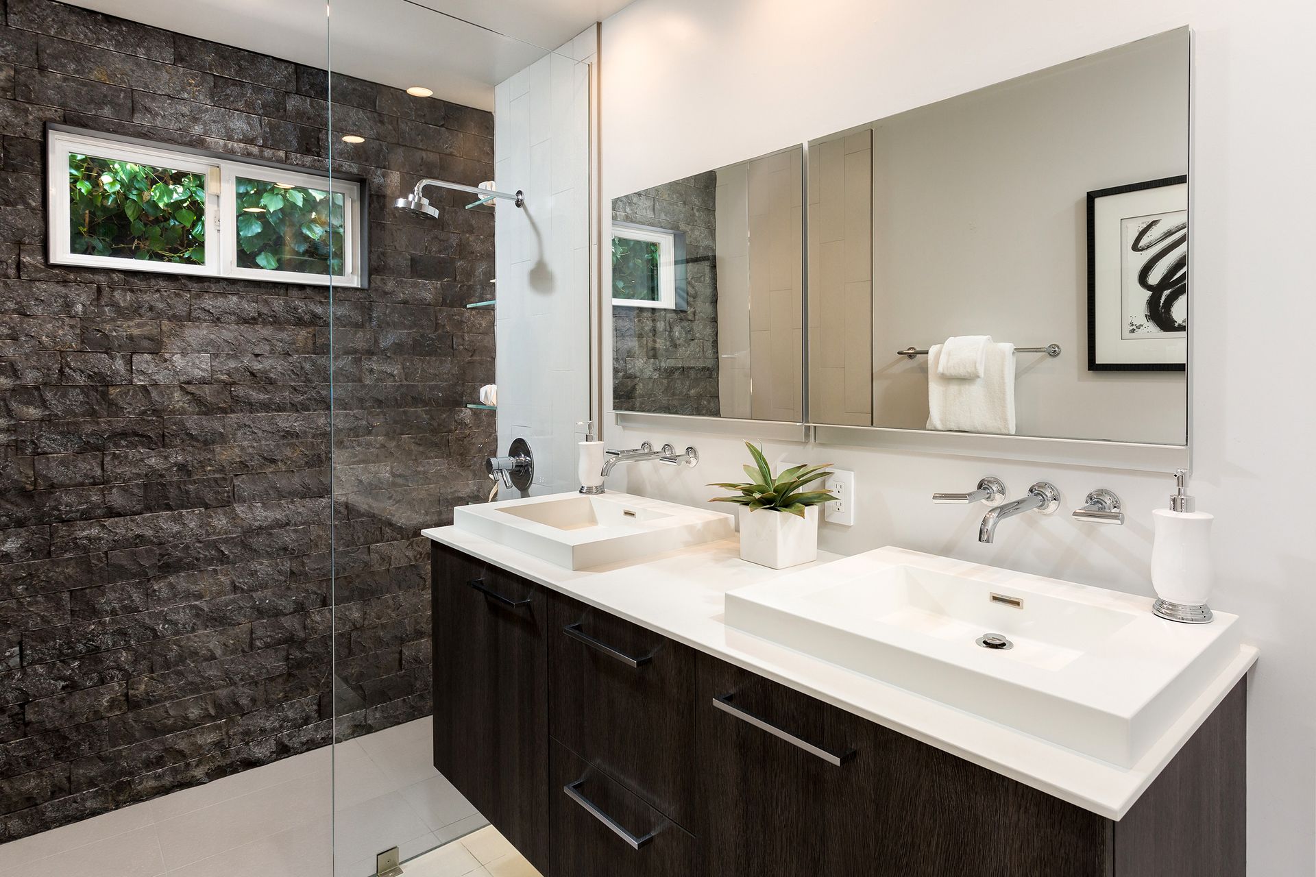 A bathroom with two sinks and a walk in shower.