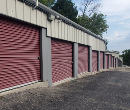 Red storage unit doors in a row, grey trim, asphalt parking.