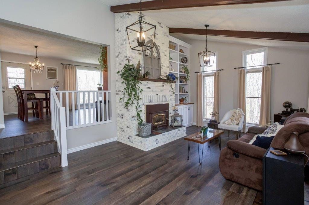 Living room with fireplace, bookshelves, and brown sofa, with a dining area in the background.