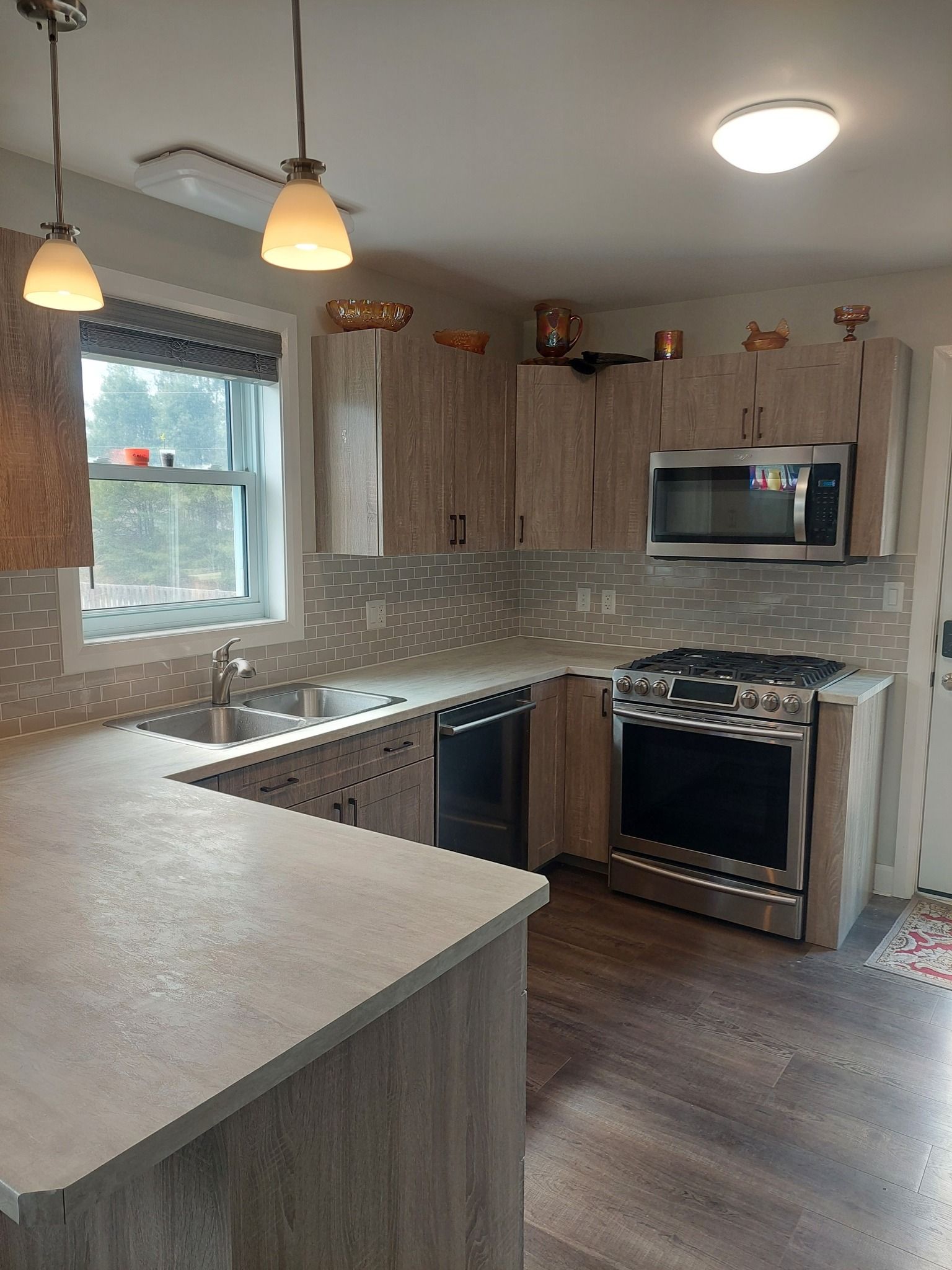 Modern kitchen with gray cabinets, countertops, and backsplash, stainless steel appliances, and wood flooring.