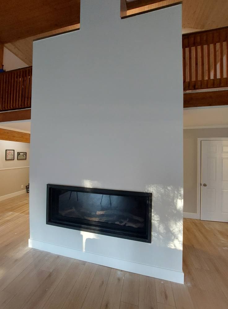 Modern fireplace built into a tall white wall, wooden floor.