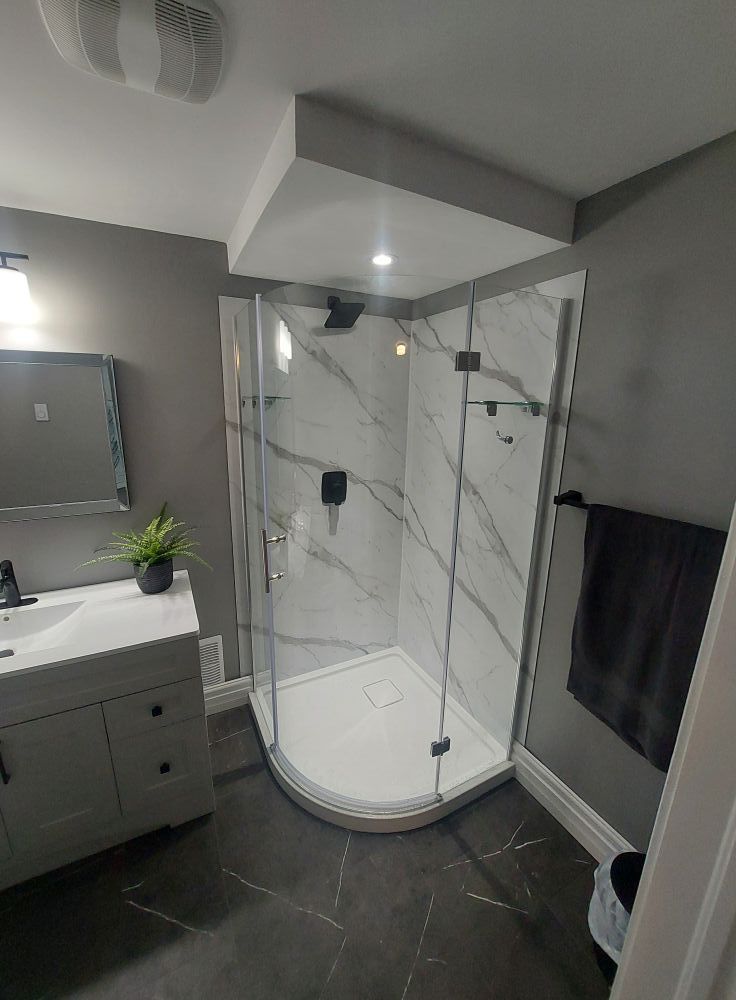 Modern bathroom with marble-look shower and gray walls. Vanity on left, towel rack on right.