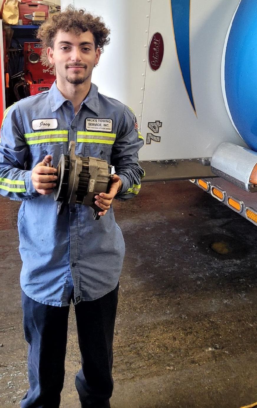 Joey Cerchione of Nick's Towing in Wallington NJ holding truck part in service bay