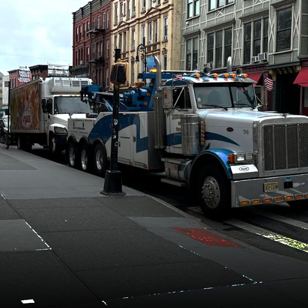 Wallington Truck Repair heavy-duty tow truck hauling a box truck in downtown Bergen County, NJ