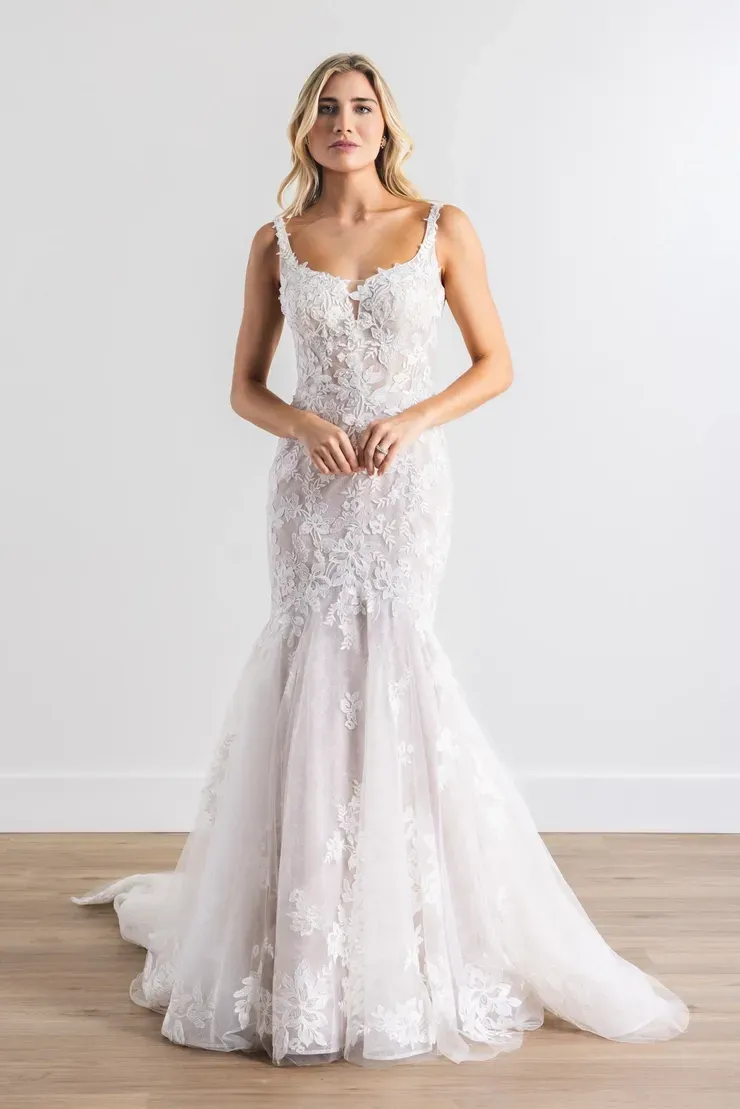 A woman in a white wedding dress is standing on a wooden floor.