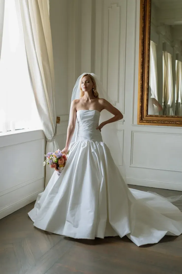 The bride is wearing a white wedding dress and holding a bouquet of flowers.