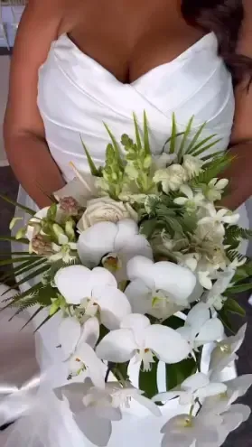 A woman in a white dress is holding a bouquet of white flowers.