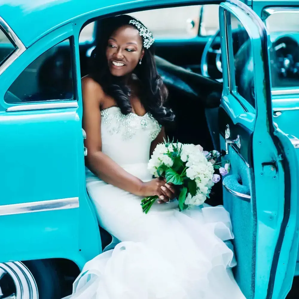 A woman in a wedding dress is sitting in a blue car