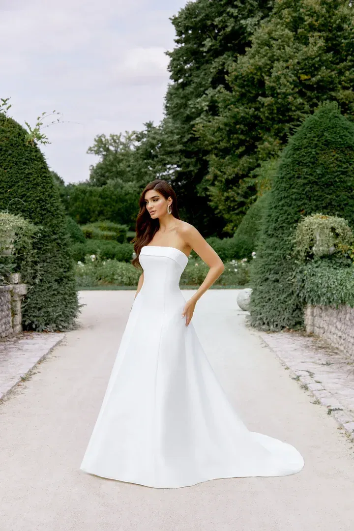 A woman in a white wedding dress is standing on a set of stairs.