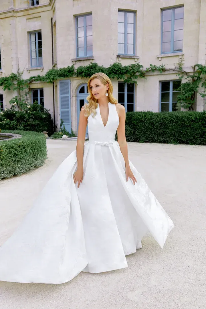 A woman in a white wedding dress is standing on a sidewalk.