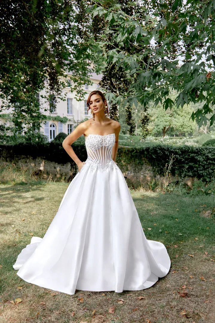 A woman in a white wedding dress is standing in front of a building.
