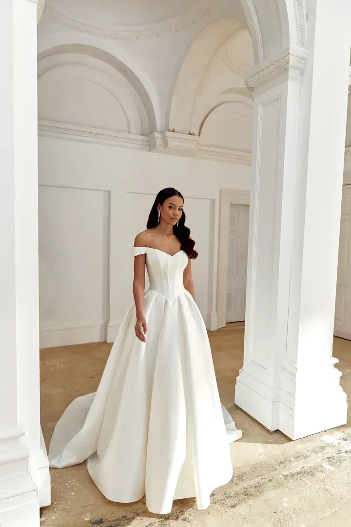 A woman in a wedding dress and veil is standing in front of a building.