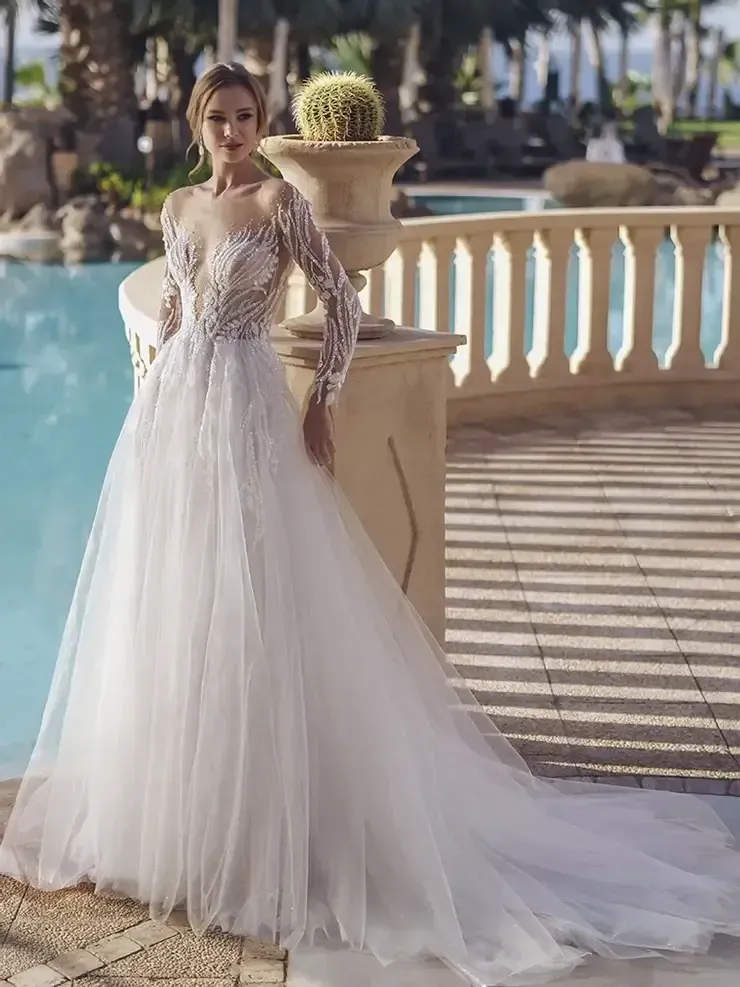 A woman in a wedding dress is standing next to a pool.