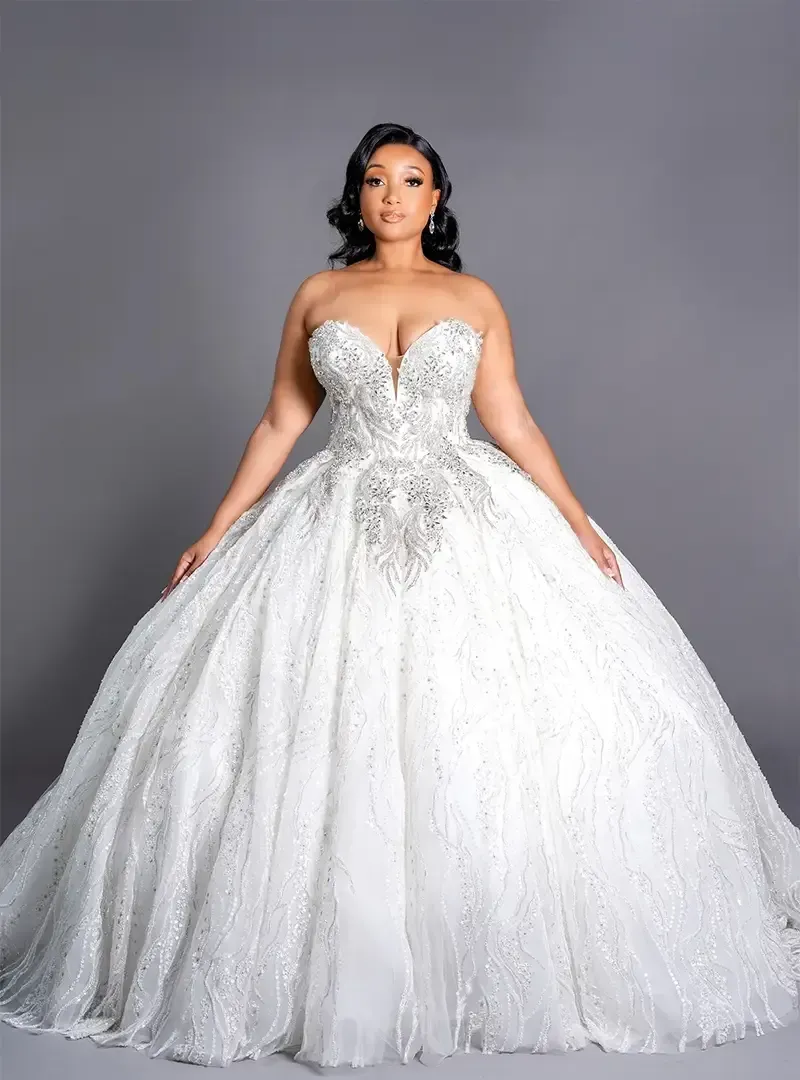 A woman in a white ball gown is standing on a gray background.