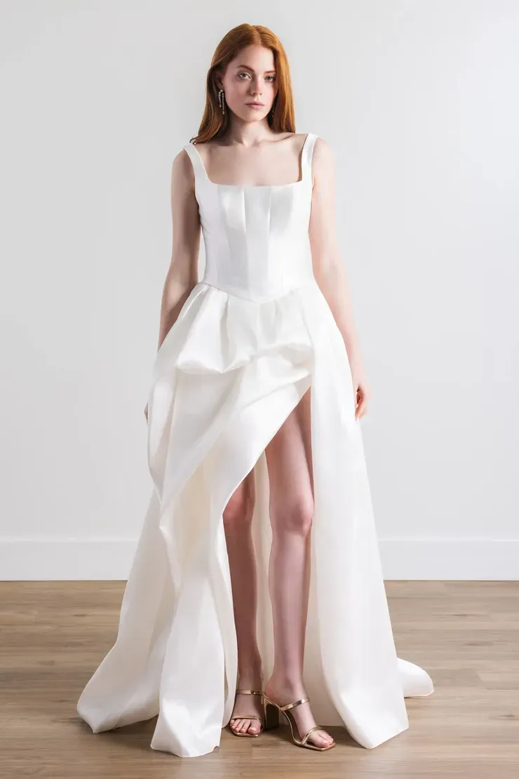 A woman is wearing a white wedding dress with a high slit.