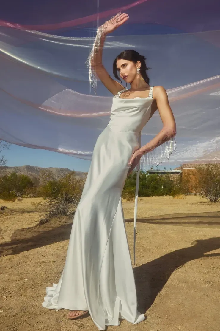 A woman in a white dress is standing in the desert.