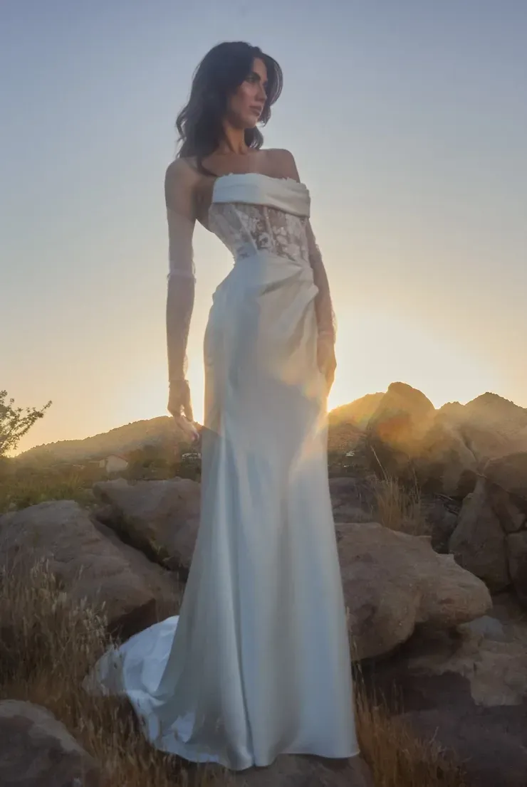 A woman in a white dress is standing on top of a rocky hill.