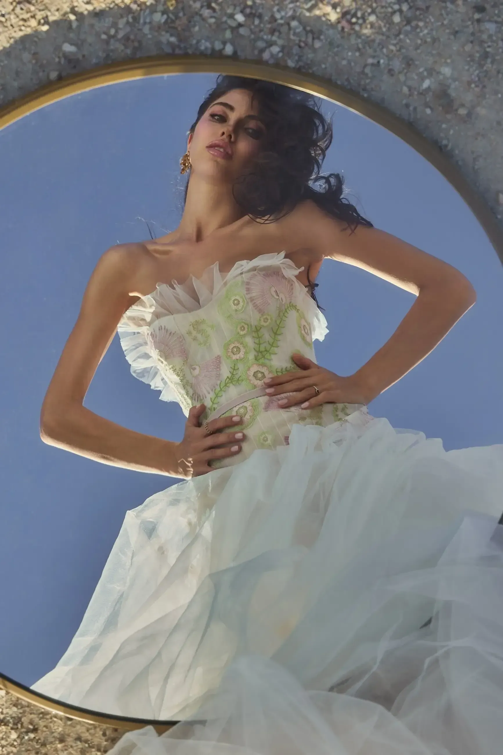 A woman in a white dress is standing in front of a mirror.
