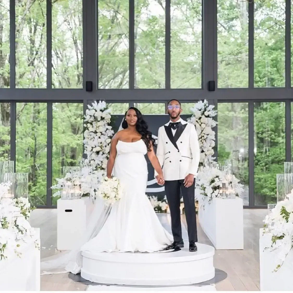 A bride and groom are posing for a picture in front of a large window.