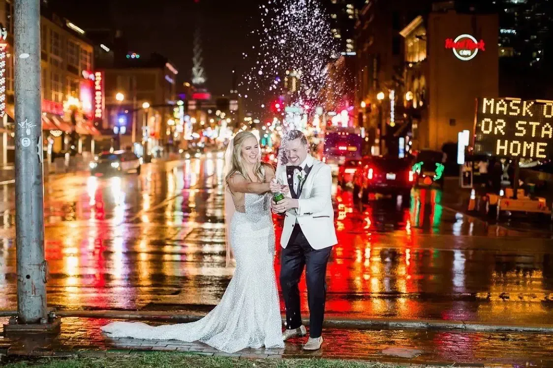 A bride and groom are posing for a picture on a city street at night.
