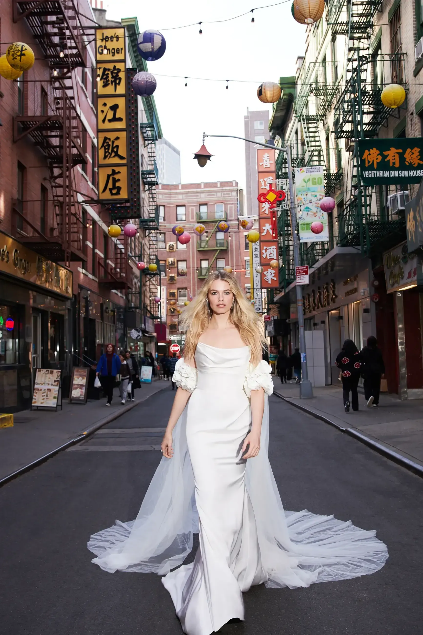 A woman in a wedding dress is walking down a city street.