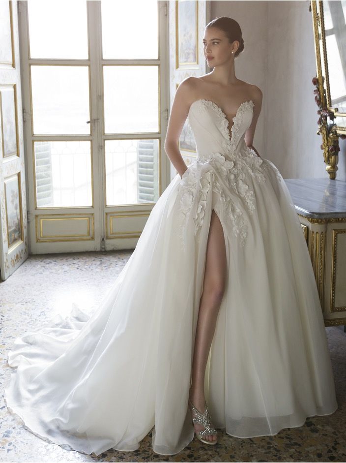 A woman in a wedding dress is standing in front of a staircase.