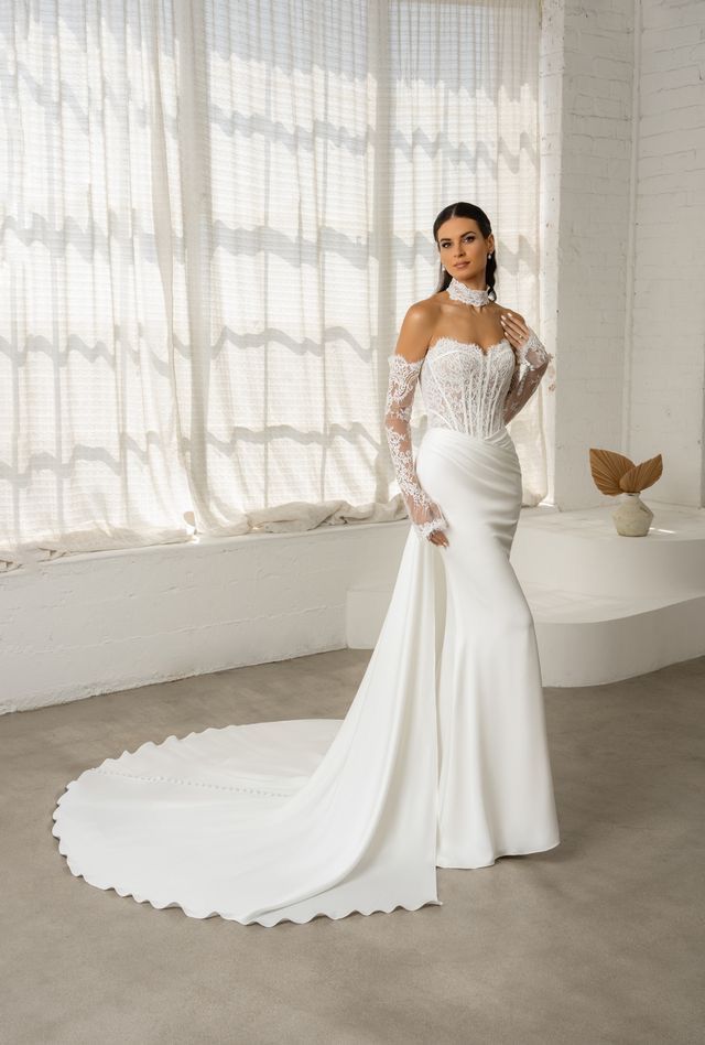A woman in a wedding dress is standing in front of a white building.