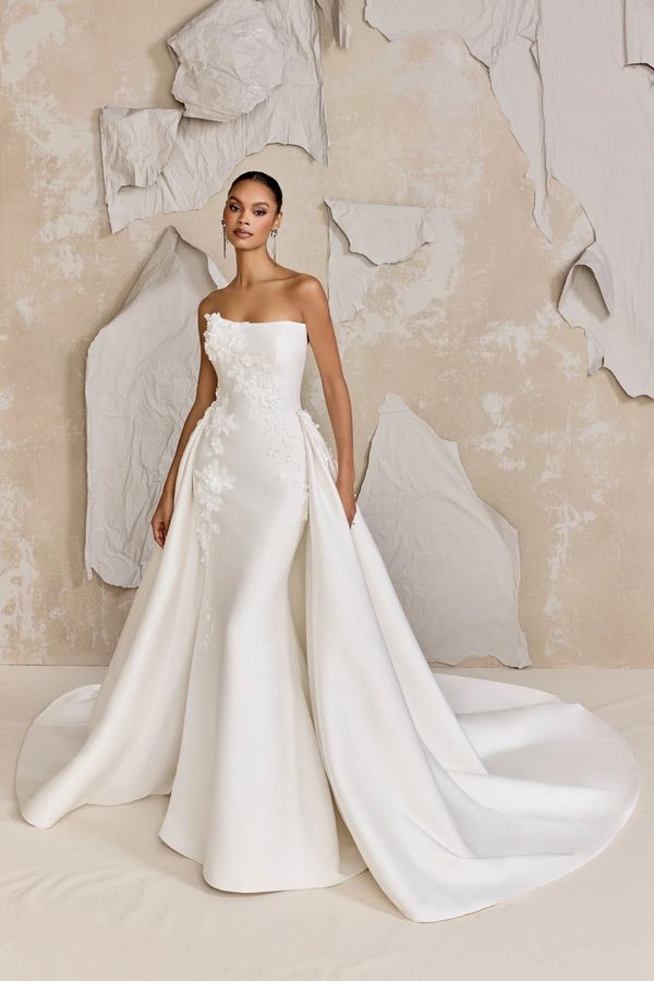 A woman is wearing a white wedding dress with a high slit.