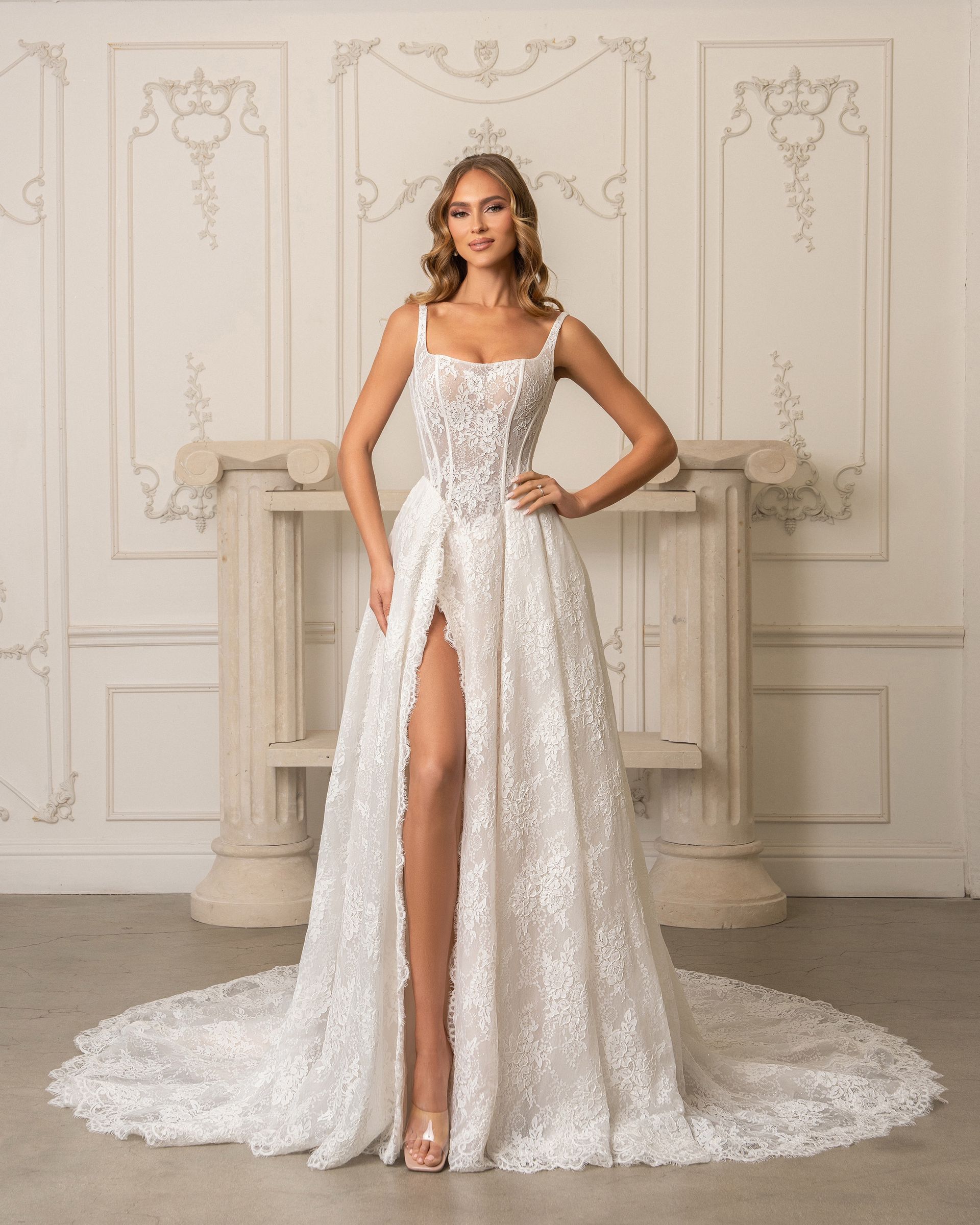 A woman is wearing a white wedding dress with feathers on the sleeves.
