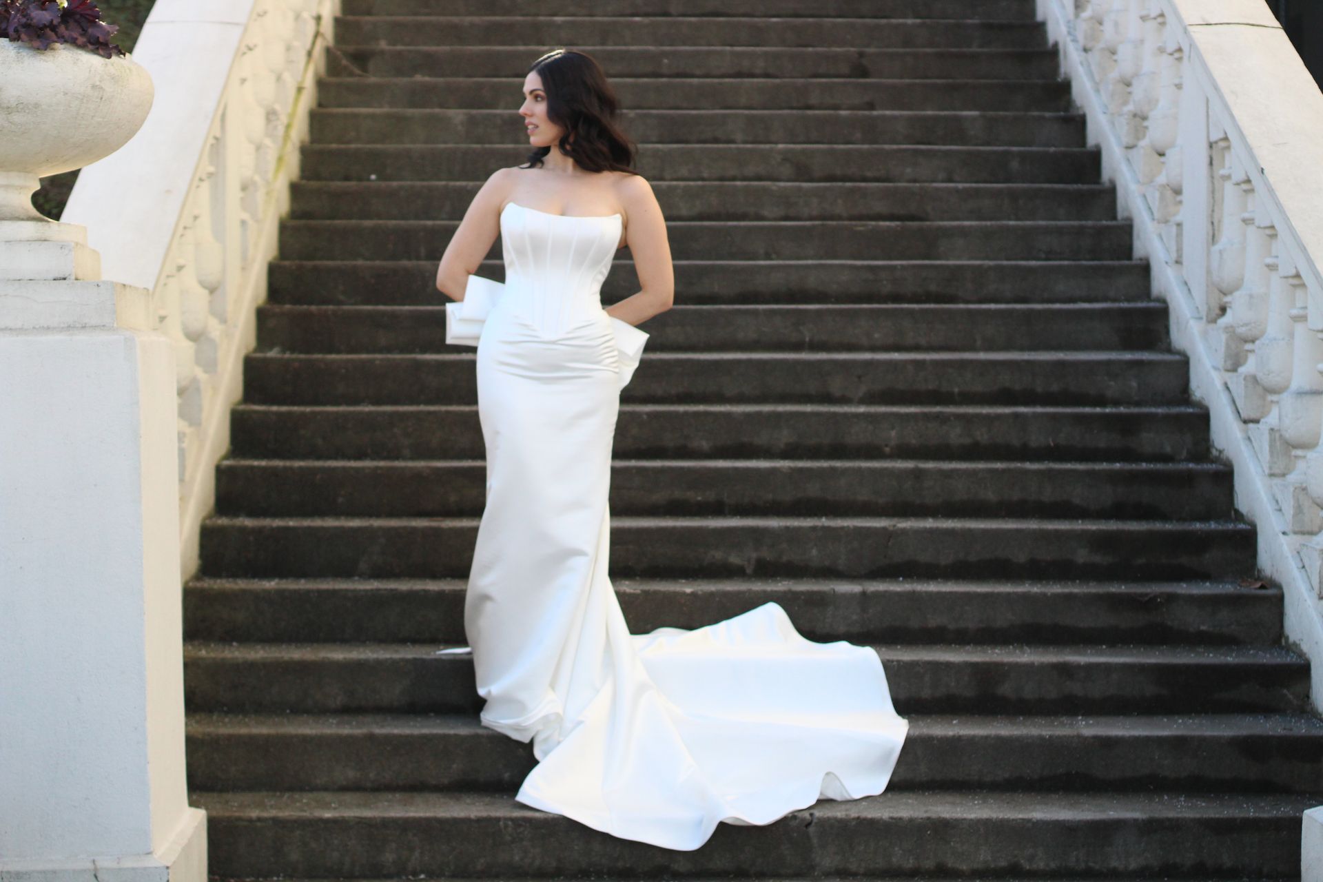 Woman in white wedding dress with pockets, standing outside.