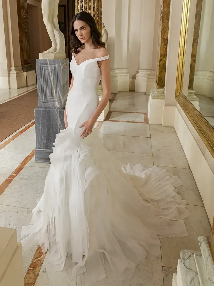 A woman in a white wedding dress is standing in a hallway.