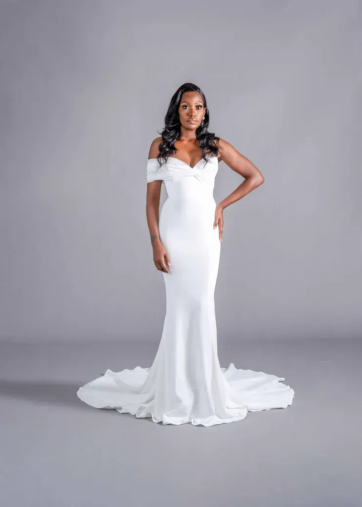 A woman in a white wedding dress is standing on a gray background.