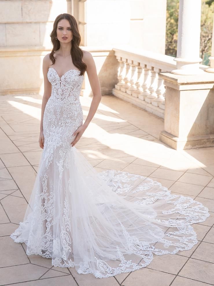 A woman in a white wedding dress is standing on a balcony.