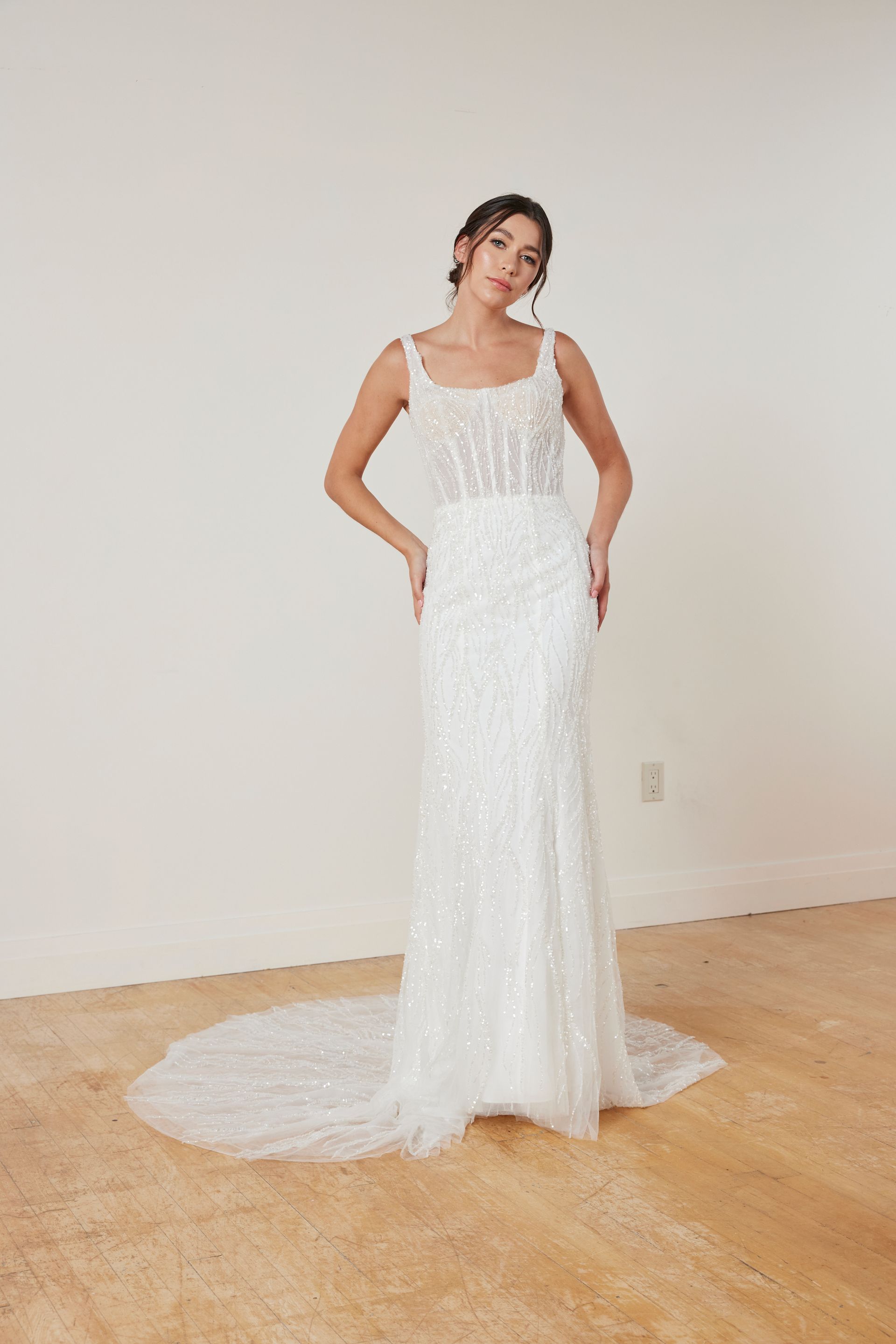 Woman in strapless white ballgown stands outdoors.