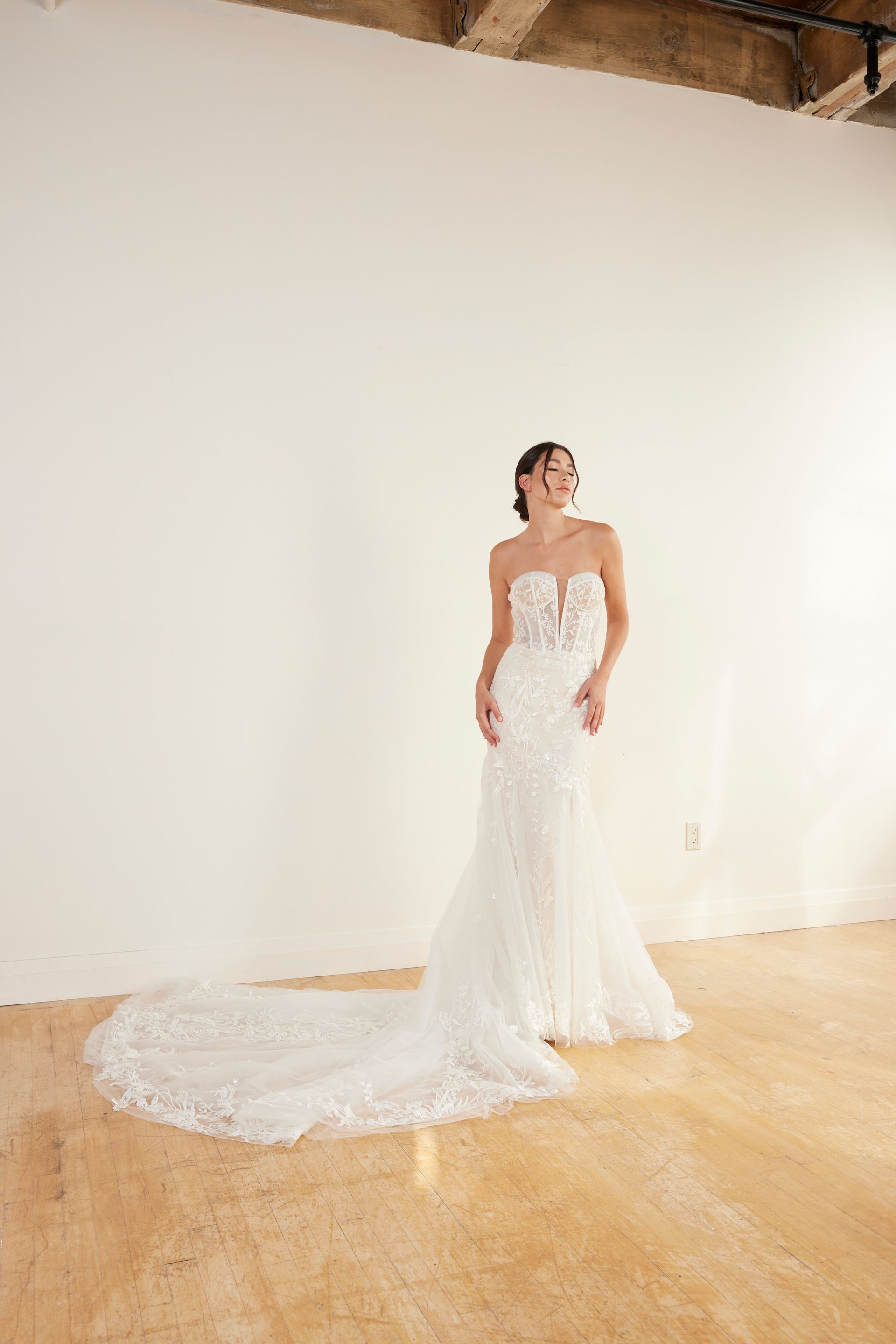 Woman in a short, embellished white dress with flowing cape, posing outdoors.