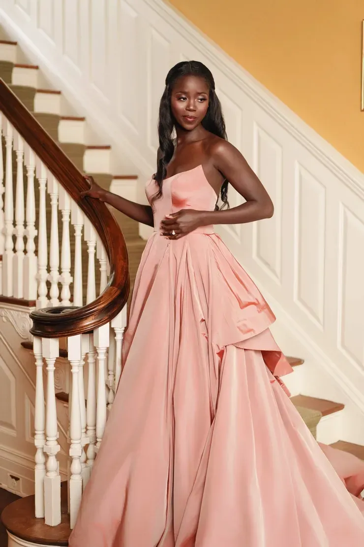 A woman in a pink dress is standing on a set of stairs.